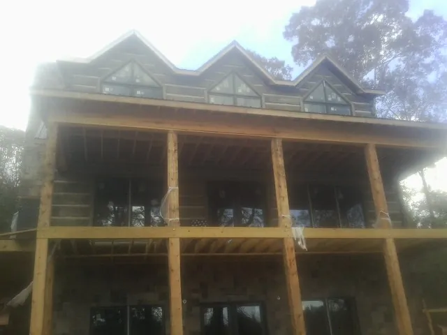 Dormers and porch framing on a large log home under construction — Roof Coating work by our crew in Almira