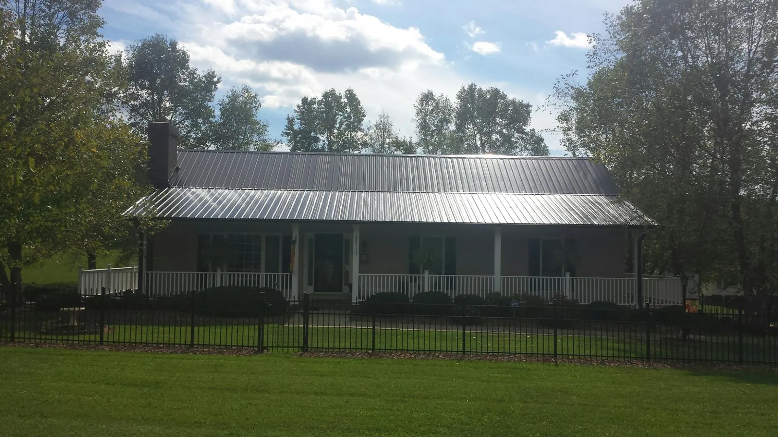 Gray metal roof on a brick ranch with a full width front porch — Gutter Guard Installation work by our crew in Almira