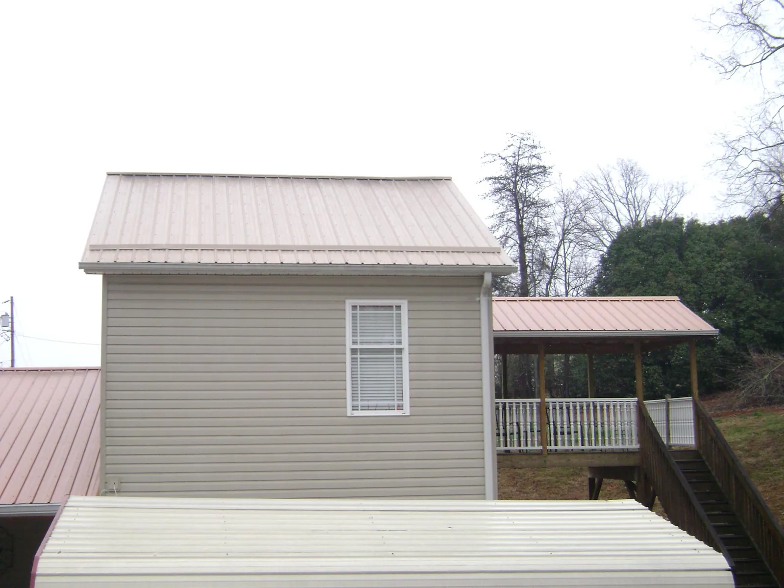 Tan metal roofs on a two story addition and attached porch, from a Roof Replacement job in Almira