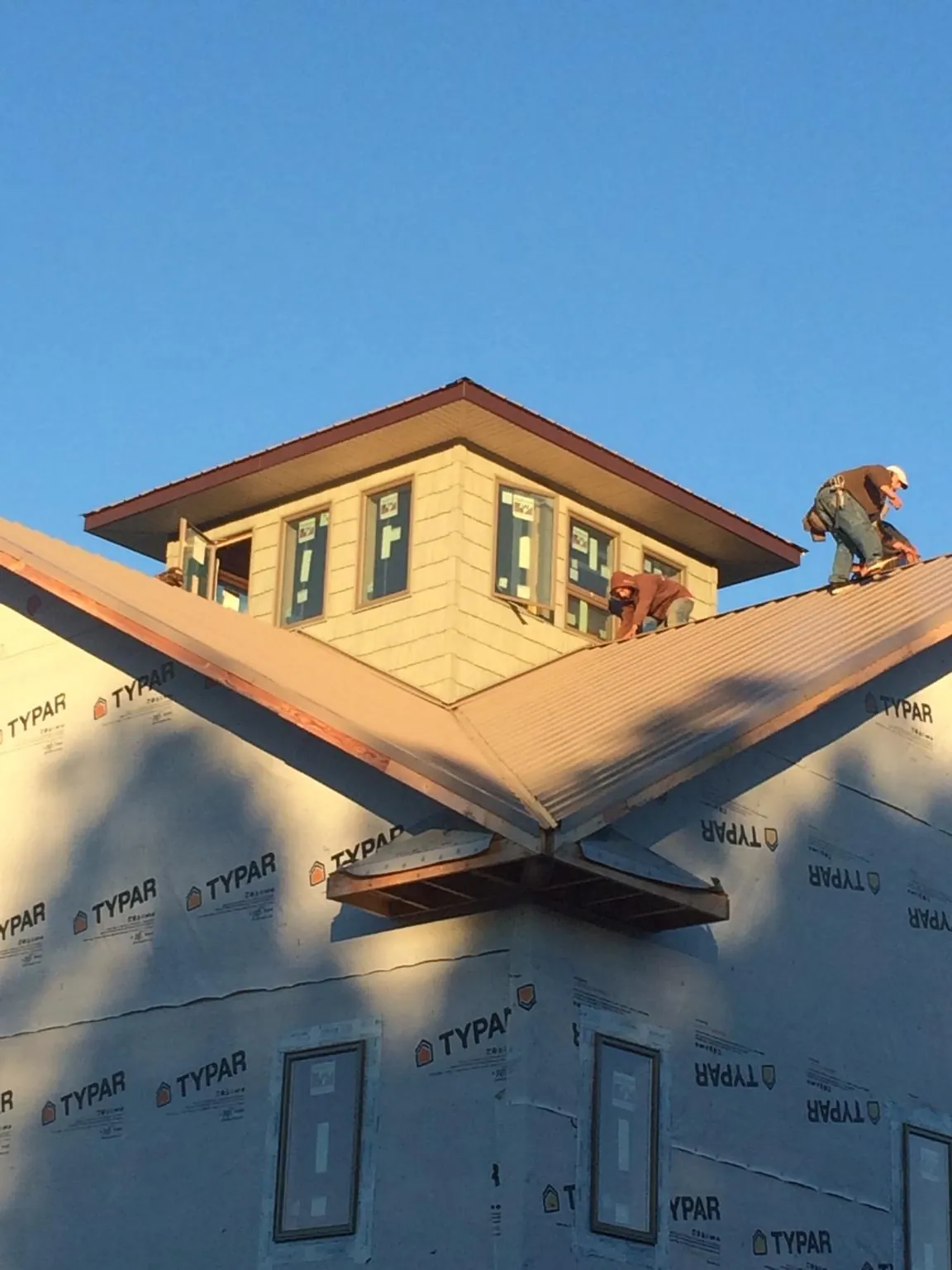 Roofers working around a rooftop cupola on a new metal roof at sunset — Roof Waterproofing in Almira by Roofing Brothers